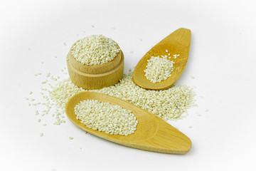 white sesame in wooden cup and spoon isolated on white background