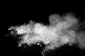 Freeze motion of white dust particles splash on black background.White powder explosion clouds.