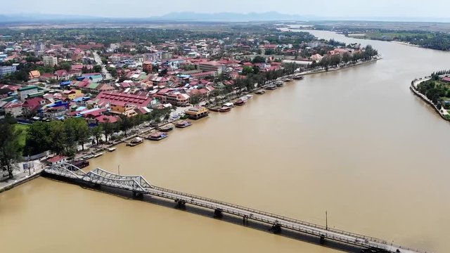 Flyover tilt up shot overlooking the neighborhoods, Praek Tuek Chhu River and mountains in Kampot, Cambodia.