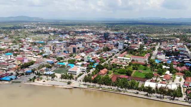 A pan to the right overlooking the city of Kampot, along with the Praek Tuek Chhu River, homes, and mountains in the background.
