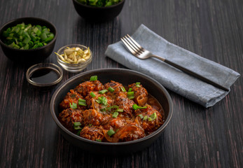 Vegetable manchurian served in a plate with soya sauce and spring onion