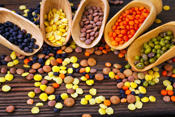 Scoops with various lentils on a wooden backround.