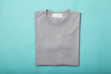 Grey folded t-shirt isolated on blue background.