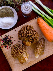 The process of cooking morel mushroom. Cutting vegetables on a wooden board. A mixture of peppers and herbal seasoning.
