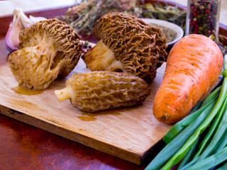 The process of cooking morel mushroom. Cutting vegetables on a wooden board. A mixture of peppers...