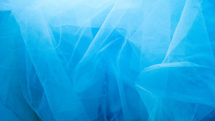 A blue tulle fabric is used as a background with copy space. Sewing concept.