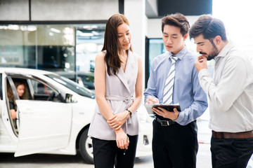 Fototapeta na wymiar Car Dealership. The Asian Salesman (woman and man) checking the list with the middle east customer before hand over. Automotive Leasing and Dealing Business. International Business.