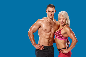 Fototapeta na wymiar Beautiful couple of muscular fit man and woman bodybuilder hugging on azure shade blue background