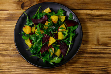 Tasty salad of fresh arugula, beetroot and oranges on wooden table. Top view. Healthy food or vegetarian concept
