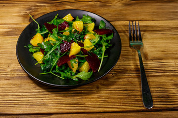 Tasty salad of fresh arugula, beetroot and oranges on wooden table. Healthy food or vegetarian...