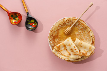 Delicious homemade pancakes with honey on a gently pink background. Top view, close-up. Traditional...