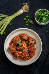 Vegetable manchurian served in a plate with soya sauce and spring onion