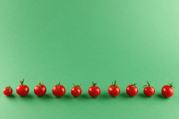 Fresh bright red tomatoes laid out in a row on a green background. Vegetarian food. Selective focus