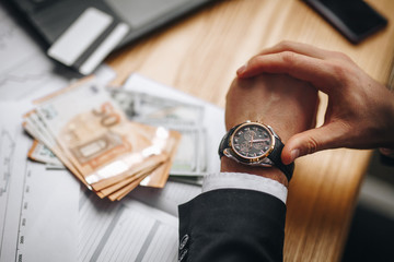 hand with a clock on the background of money in the office