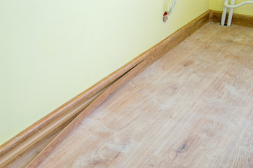 Installing decor strip of floor plastic skirting boards.