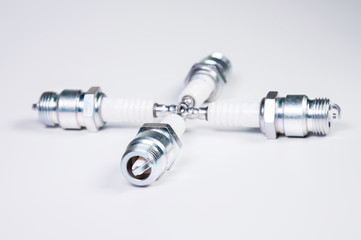 Obraz premium Subject shooting on a gray background. new four spark plugs, spare parts for a gasoline engine. The concept of new auto parts and maintenance
