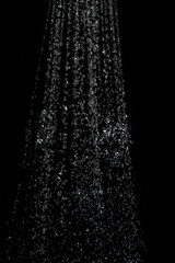 Blurred background with a stream of water splashing out of the shower against a dark background. Image to use as an element or background mock up