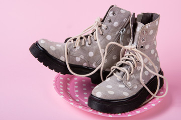 a pair of demi-season shoes made of fabric with peas, on a pink cardboard plate with peas, on a pink background, the concept of seasonal shopping