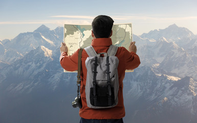 A young traveler man on the top of iceberg mountain with backpack in the nature and look searching direction on location map, Adventure and travel in the mountains region concept