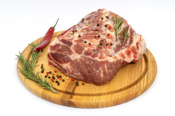 Fresh raw pork neck on wooden board isolated on white. Rosemary, pepper, bay leaf with meat.