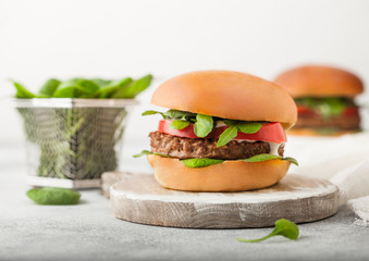 Healthy vegetarian meat free burgers on round chopping board with vegetables and spinach on light table background.