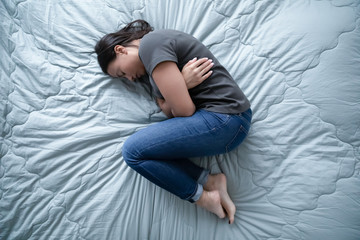 Unhealthy young woman lying in bed feeling depressed