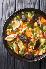 Mushroom soup with chickpeas and vegetables close-up in a bowl. Vertical top view