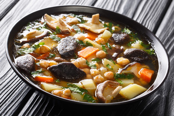 Tasty fresh soup with mushrooms, vegetables and chickpeas close-up in a bowl. horizontal