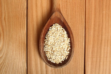 Barley groats on wooden spoon at plank background. Directly Above.
