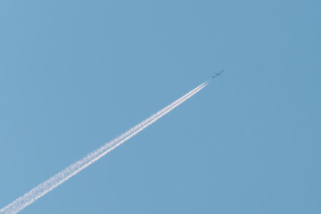 Jet passenger plane with reversing trail on a background of blue sky
