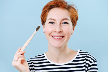 Happy woman with short ginger hair recommending a wooden toothbrush
