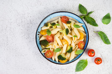Boiled Penne with vegetables, broccoli, tomatoes and fresh herbs. Top view, copy space.