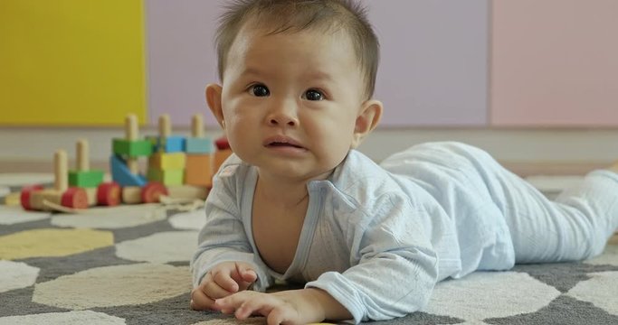 Asian baby crawing on floor in living room, scare and afraid. Childhood and nursery service concept.