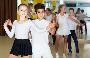 Group of smiling children dancing salsa in school