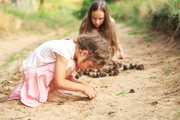 Fototapeta premium Cute Happy Little girl play with sand in park on a summer day at sunset.