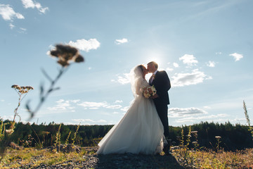 Silhouette of the bride and groom against the sky at sunset. newlyweds stand against the sky