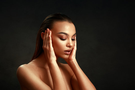 Closeup portrait of beautiful young woman with nice and clean skin with subtle makeup and wet hair on a dark background