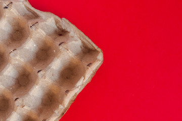 An empty craft egg carton on the red background. View from above. Top view. Copy space