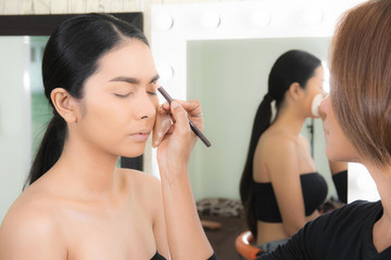 Woman applying makeup by makeup artist.