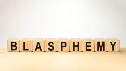 blasphemy word concept written on wooden cubes on a light table and a light white background