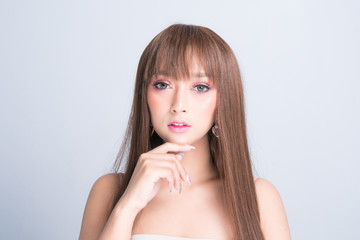 Naklejka premium Beautiful young woman with clean fresh skin, long hair sleek isolated on gray background. With copy space.