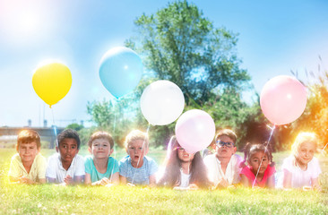 Fototapeta premium Children with balloons posing on grass in park at sunny day