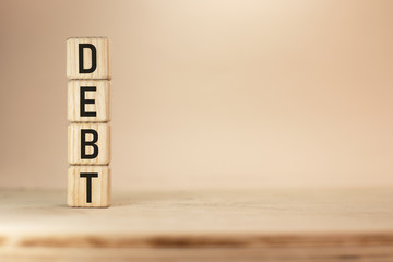 Word Debt written with wooden blocks on beige background