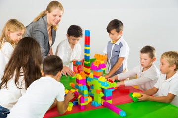 Kids with teacher playing with building blocks