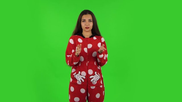 Beautiful girl in red fleece pajamas is clapping her hands indifferent. Green screen