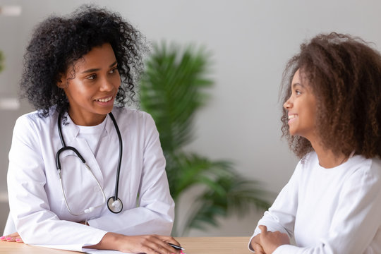 Friendly African American Female Doctor Talking To Teen Girl Patient