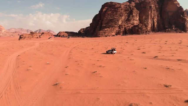 Flying behind off-road jeep while driving it is driving through the epic Wadi Rum desert in Jordan