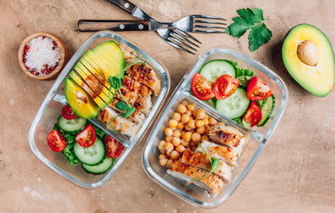 Healthy meal prep containers with chickpeas, chicken, tomatoes, cucumbers and avocados. Healthy lunch in glass containers on beige rustic background. Zero waste concept. Selective focus.