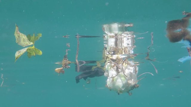 Plastic waste pollutes ocean. Underwater video of bags, cups, bottles and straws pollution in the sea 