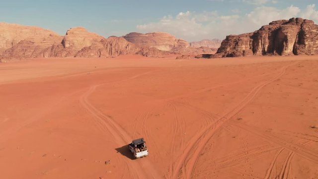 Aerial shot from above with group of people driving in off road vehicle in the middle of the Wadi Rum desert,  Jordan